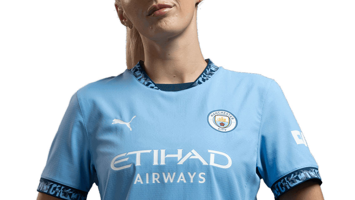 A female individual wearing the Manchester City 2023/24 Puma home kit with Etihad Airways as the sponsor.